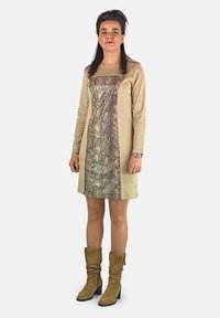 Vestido beige con un panel central de estampado de serpiente, mangas largas y escote cuadrado. Complementado con botas de gamuza color marrón claro hasta la rodilla.