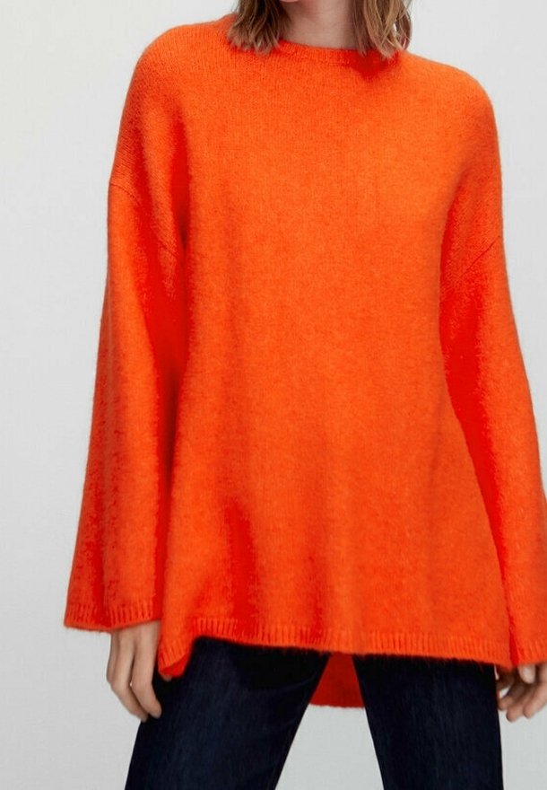 Pull oversized orange vif avec manches longues, fabriqué en tissu tricoté texturé. Présente une coupe décontractée et un ourlet arrondi.