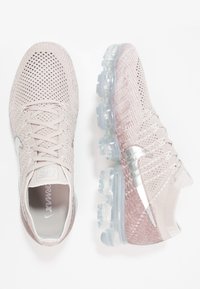 Nike Air VaporMax sneakers in lichtroze mesh met een transparante zool. Voorzien van een zilveren swoosh en een gestructureerd bovenwerk met vetersluiting.