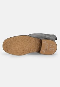 Calzado negro con una suela de goma texturizada, con una capa de corcho marrón claro. Talla 37 impresa en la suela con detalles de la marca en relieve.