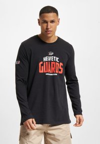 Zwarte lange mouwen T-shirt van katoen, met een grafische print "HELVETIC GUARDS" in rood en wit. Ronde halslijn met logo op de mouw.