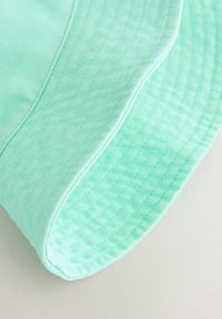 Minzgrüner Bucket-Hut mit einer strukturierten, gesteppte Krempe und glattem Stoff. Verfügt über eine abgesteppt Naht entlang des Randes, die seine Form betont.