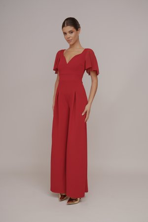 Rød jumpsuit med korte, utsvingte ermer og dyp V-hals. Har en tettsittende bodice og brede ben med folder. Gyldne spisse hæler.