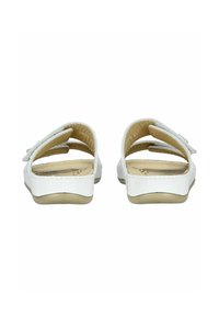 White sandals with a flat sole, featuring a dual strap design. Smooth texture and a light cream lining enhance comfort and fit.