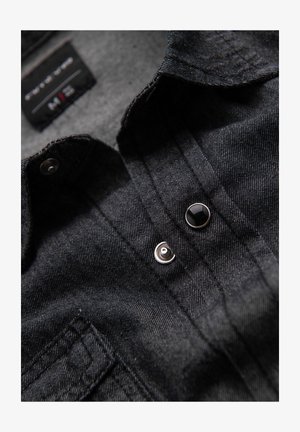 Černá džínová košile s předním zapínáním na knoflíky, kovovými knoflíky a jemnými vertikálními švy. Měkká textura a neformální design.