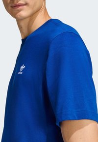 Μπλε βαμβακερό t-shirt με στρογγυλή λαιμόκοψη και κοντά μανίκια. Διαθέτει λευκό κεντημένο λογότυπο Adidas στο στήθος. Ομαλή, ελαφρώς εφαρμοστή υφή.