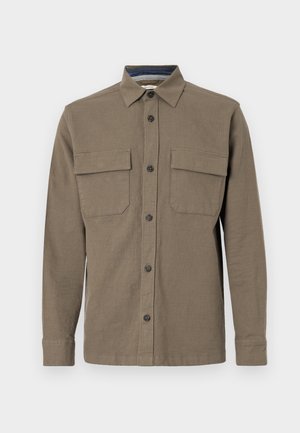 Camisa abotonada en verde oliva con mangas largas, dos bolsillos en el pecho y un cuello recto. Fabricada en tejido texturizado con costuras visibles.