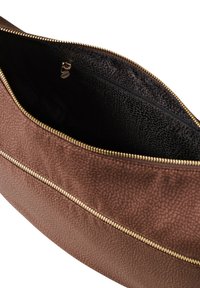 Bolso marrón con textura y cremallera dorada, con exterior liso y interior forrado en negro que incluye un bolsillo adicional con cremallera.