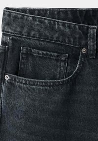 Gros plan d'un jean en denim noir délavé montrant la poche avant, la petite poche à monnaie, la boucle de ceinture et les détails des rivets métalliques.
