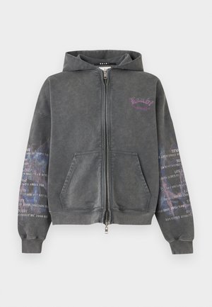 Sweat à capuche zippé gris foncé avec poches avant, logo texte violet sur la poitrine et motif de texte imprimé blanc sur les deux manches.