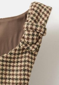 Bruin en crème hondenbeetpatroon stof met een gestructureerde afwerking, voorzien van een ronde gespdetail op de verstelbare riem.