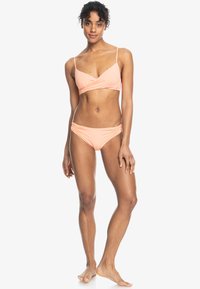 Persikofärgad tvådelad bikini med en wrap-stil topp med tunna band och rynkade sidodetaljer på trosorna, tillverkad av slät, elastisk tyg.