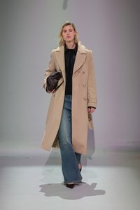 Beige divreizējs mētelis, melna blūze, plati zili džinsi un tumši brūna soma. Gluda auduma, strukturēts dizains un smailas kurpes.