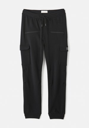 Pantalons de survêtement noirs en mélange de coton, dotés d'une taille élastique avec cordon de serrage, de deux poches zippées et de poches cargo latérales pour plus de praticité.