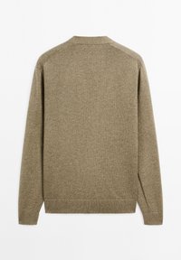 Beige stickad tröja med rund hals, ribbad ärmslut och nederkant. Slät textur, långa ärmar och en enkel baksida utan några ytterligare detaljer.