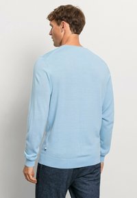 Hellblauer Strickpullover mit rundem Halsausschnitt und langen Ärmeln. Texturiertes Material, gerippte Bündchen und Saum, minimale Markenkennzeichnung an der Seite.