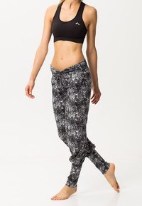 Höga, svart- och gråmönstrade joggerbyxor tillverkade av elastiskt tyg, med smal midja vid ankeln och lös passform runt höfterna.