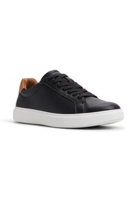Sneaker in pelle nera con superficie texture, suola in gomma bianca e un accento in pelle marrone sul tallone. Presenta lacci neri.