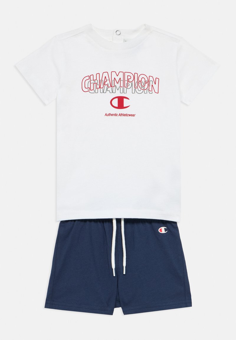 Λευκό βαμβακερό T-shirt με κόκκινο γραφικό "Champion", σε συνδυασμό με σκούρα μπλε σορτς που διαθέτουν λογότυπο και κορδόνι, και τα δύο casual και ελαφριά.