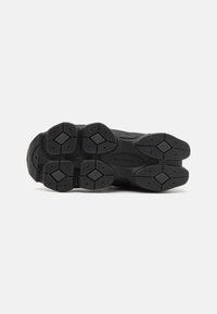 Semelle de sneaker noire avec caoutchouc texturé, motif de semelle en forme de diamant et détail de logo, conçue pour l'adhérence et la durabilité.