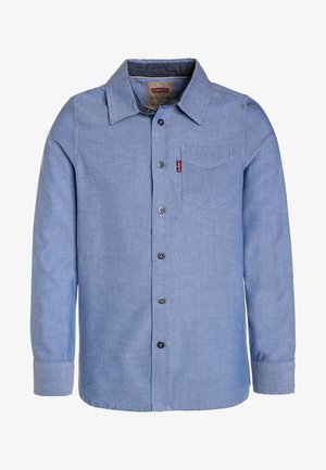 Světle modrá košile na knoflíky vyrobená z denimu. Obsahuje špičatý límec, dlouhé rukávy, jednu náprsní kapsu a značkovou etiketu na kapse.