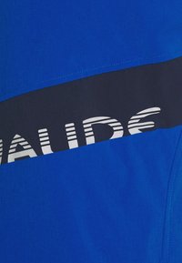 Sininen tekstiili, jossa on tummansininen vaakaraita, jossa lukee "LAUDE" valkoisella, korostettuna raidallisella kuviolla, sileä pinta.