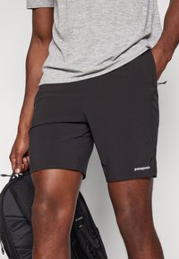 Μαύρα μαγιό από ελαφρύ ύφασμα, με κορδόνι στη μέση, πλαϊνές τσέπες και το λογότυπο της Patagonia στο κάτω κομμάτι.