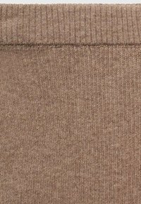 Brun stickad tyg med ribbad textur, som visar subtila färgvariationer och ett enhetligt mönster genomgående.