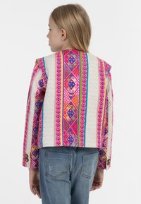 Spalvingas raštuotas švarkas su rožinėmis, mėlynomis ir kreminėmis geometrinėmis formomis; turi liesą siluetą ir mygtukus ant rankovių.