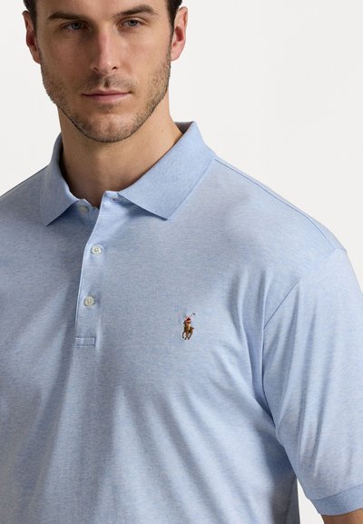 Polo de culoare albastru deschis, realizat dintr-un amestec de bumbac, cu un guler cu două butoane, mâneci scurte și un mic logo brodat pe piept.