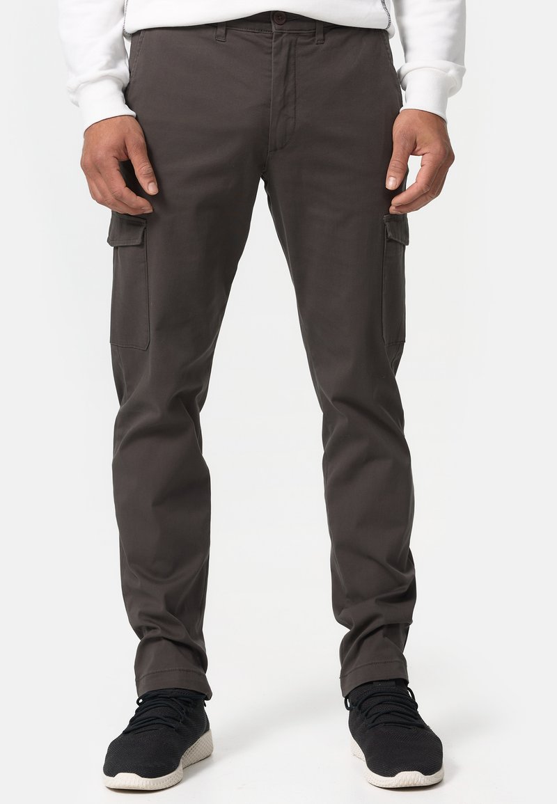 Cargo pants in dark grey fabric with a slim fit, featuring side pockets and subtle stitching details. Worn with black athletic shoes.
