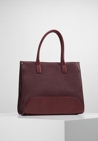 Burgundowa skórzana torba typu tote z teksturowanym korpusem i gładką podstawą, wyposażona w dwa wytrzymałe uchwyty oraz delikatne przeszycia.