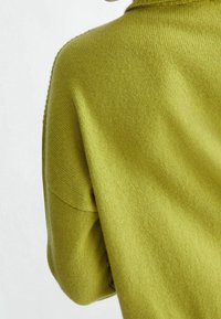Maglione verde lavorato a maglia con una texture morbida, caratterizzato da una vestibilità ampia e da un delicato dettaglio a coste lungo il colletto e le maniche.