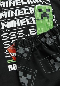 Schwarze Kleidung mit wiederholtem weißen Blocktext "MINECRAFT" und pixeligen grünen und roten Creeper-Gesichtern aus dem Spiel Minecraft.