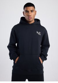 Black hoodie made of cotton blend, featuring a front pocket and a small white graphic design on the left chest area. Textured fabric.