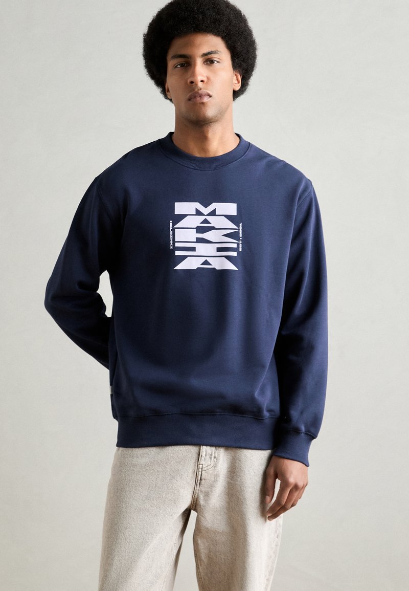 Sudadera azul marino con un estampado gráfico en blanco. Presenta un cuello redondo y puños y dobladillo acanalados. Hecha de una tela suave.