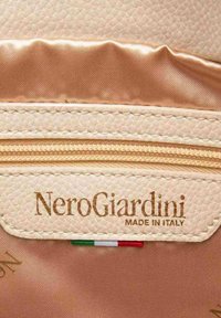 Etichetta in pelle tessurizzata beige chiaro con "NeroGiardini MADE IN ITALY" impresso. Fodera in satin rame con una finitura liscia.