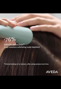 Applicateur de traitement du cuir chevelu Aveda, vert menthe, au design ergonomique, tenu au-dessus de cheveux sombres et brillants ; le texte superposé affiche une statistique de réduction du sébum.