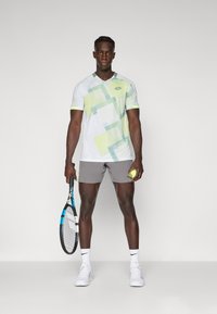 Men's tennis outfit featuring a white and light green patterned shirt with short sleeves, gray shorts, a tennis racquet, and a tennis ball.