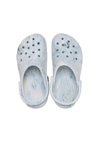 Zuecos blancos sin cordones con un diseño en azul y amarillo veteado. Presentan orificios de ventilación y una correa trasera para un ajuste seguro. Suela texturada.
