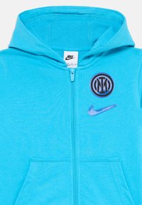 Haut en zip bleu vif avec capuche, poches avant, étiquette Nike à l'intérieur du col, blason du club Inter Milan et swoosh Nike sur la poitrine.
