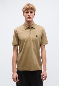 Polokošeľa s krátkym rukávom z olivovo zelenej bavlny, s golierom a trojgombíkovým zapínaním, s čiernou logovou nášivkou na hrudi.