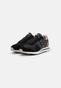 Schwarze Sneakers mit einem Obermaterial aus Wildleder und Mesh, grauen Akzenten, reflektierenden Details, einer gepolsterten Sohle und einer orangen Gummisohle.