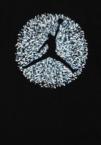 Black shirt featuring a circular graphic with a silhouette in mid-air holding a basketball, surrounded by a pattern of blue and white speckles.