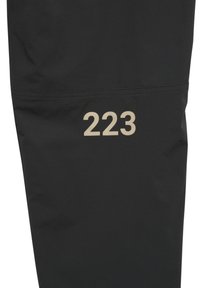 Schwarze Hose aus leichtem Material mit schlankem Design und einer auffälligen beigen Zahl "223" am unteren Bein.