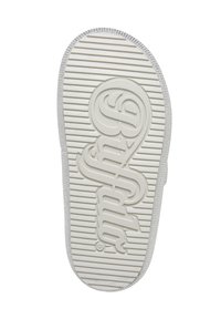 Semelle de chaussure en caoutchouc blanc avec rainures horizontales et logo stylisé en relief "Superdry" au centre du bas.