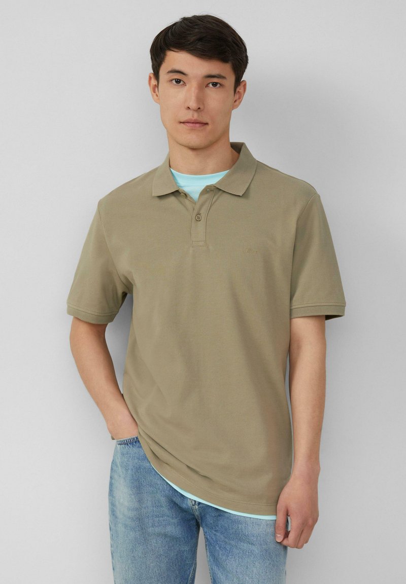 Khaki polo-shirt met een klassieke kraag, korte mouwen en een subtiel textuurpatroon. Draag het over een lichtblauw T-shirt. Casual pasvorm.