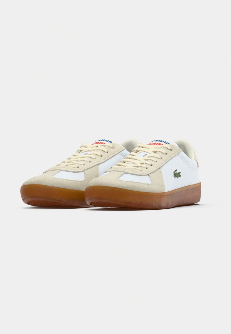 White leather and beige suede sneakers with a rubber sole, featuring lace-up closure and lacoste logo embroidered on the side.