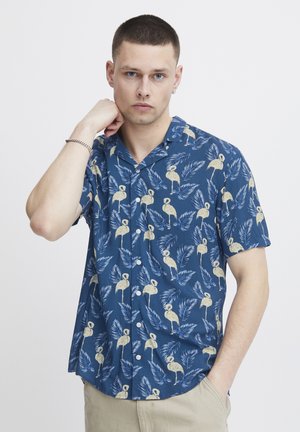Short-sleeve shirt in blue fabric with a flamingo and leaf pattern, featuring a button-up design and a collar. Smooth texture, casual fit.
