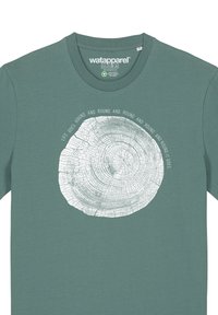 Grünes Baumwoll-T-Shirt mit einem runden Baumring-Graphic in Weiß und dem Text "Das Leben dreht sich im Kreis." Runder Ausschnitt.